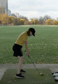 GIF of Julie Young swinging a golf club at a driving range.