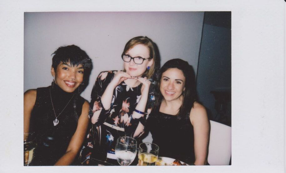 Polaroid of Julie Young posing at a table with two other women.